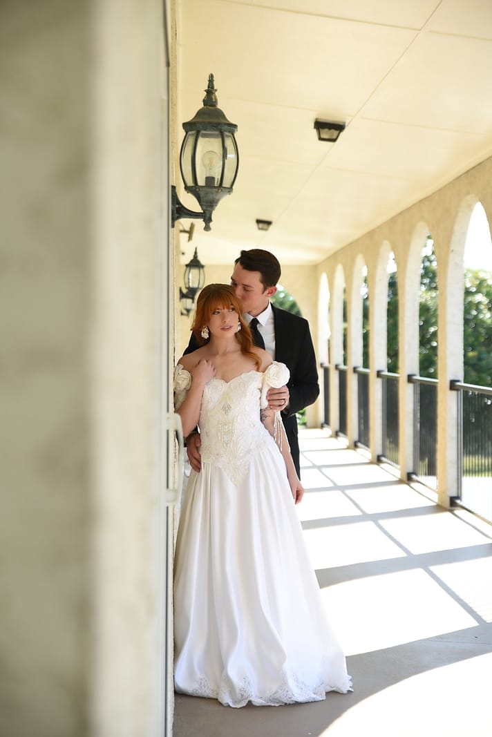 A bride holding her dress fabric and showing her bouquet of burgundy, pampas grass, and roses against a wood background — North Georgia detail photo